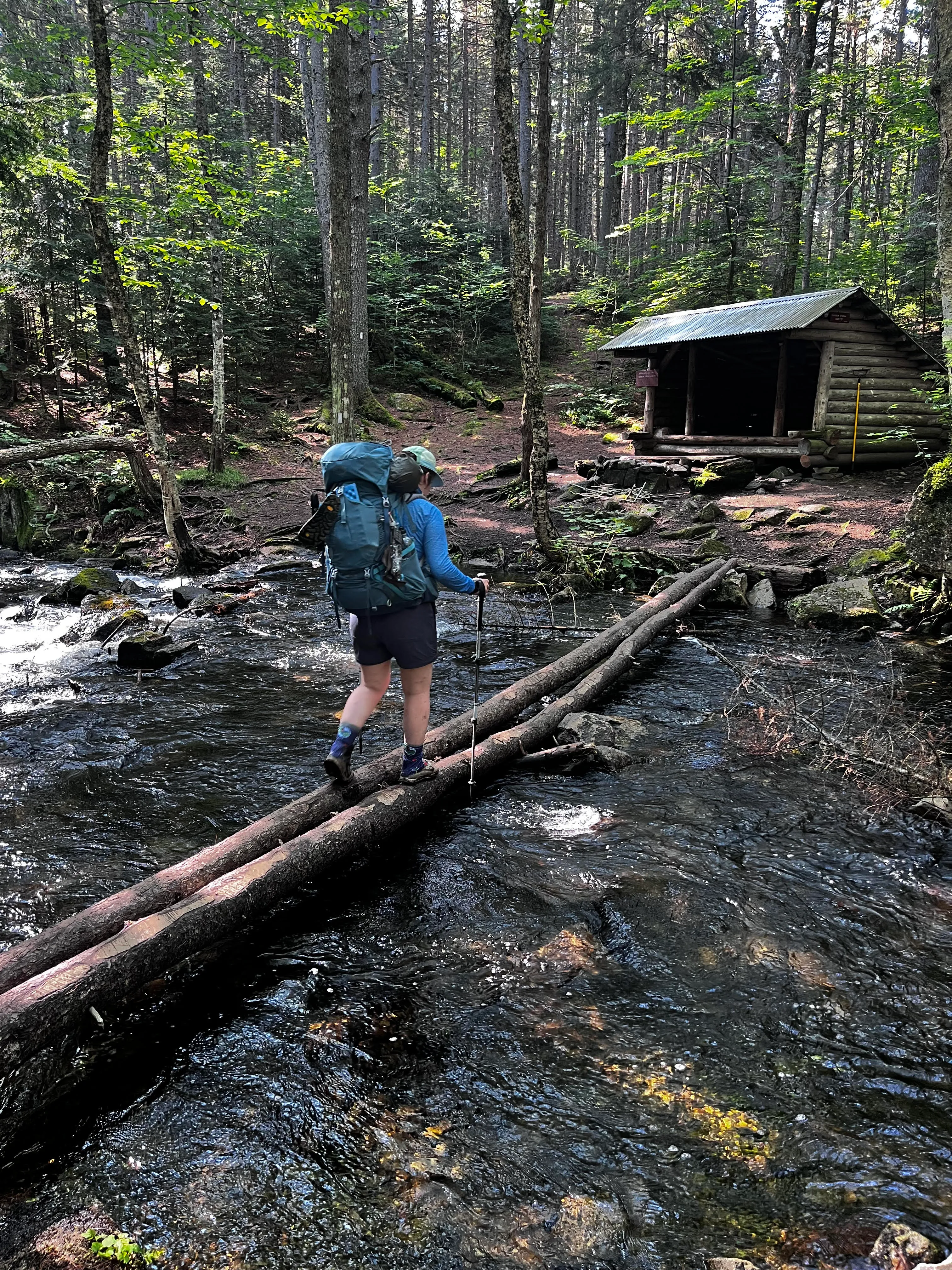 Hiker crossing a river in the 100 Mile Wilderness